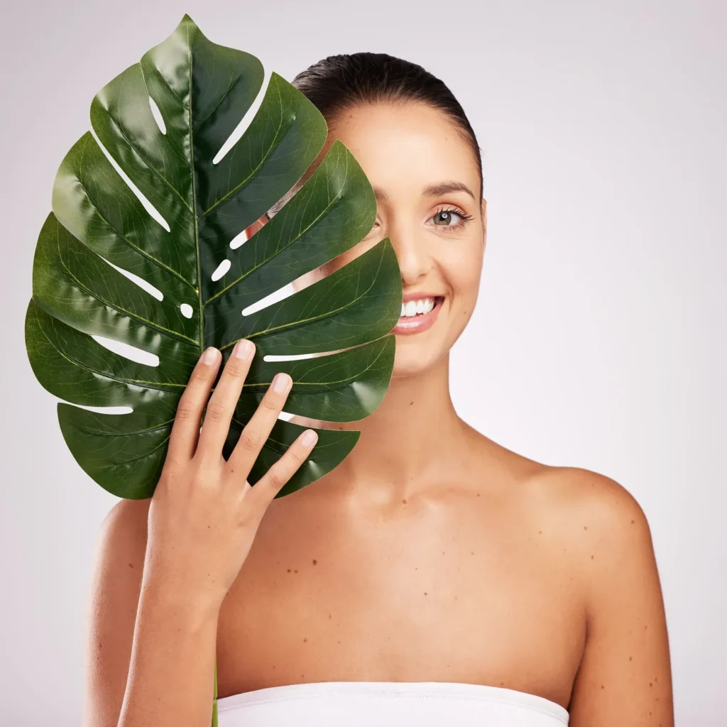 Woman holding a large tropical leaf beside her face