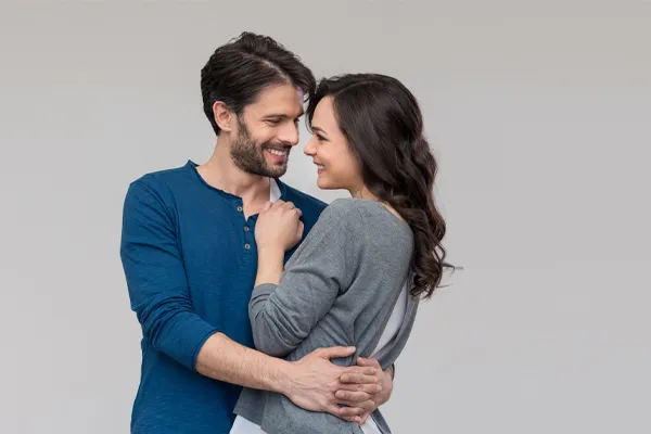 Erectile-Dysfunction-Doctor A man in a blue shirt embracing a woman in a gray shirt smiles due to his successful erectile dysfunction care from Blessed Beauty Boutique in Greater Phoenix.
