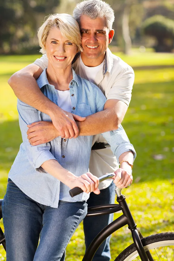 HCG-Weight-Loss-Treatment A mature couple embrace smiling and standing outside by a bike. Get the HCG for weight loss treatment from Blessed Beauty Boutique in Greater Phoenix.