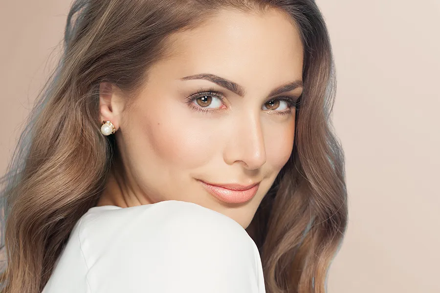 Jueveau-Facial-Injections-Clinic A woman with long brown hair and radiant skin. Get Jueveau facial injections from Blessed Beauty Boutique in Greater Phoenix.