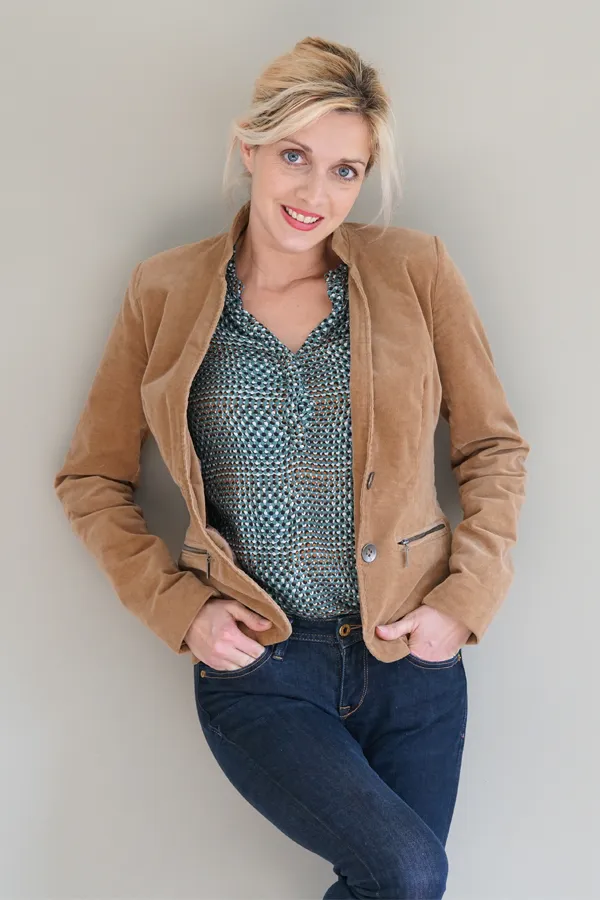 Metabolic-Syndrome-Treatment A blonde woman in a tan leather jacket leans against a gray wall. Get metabolic syndrome from Blessed Beauty Boutique in Greater Phoenix.