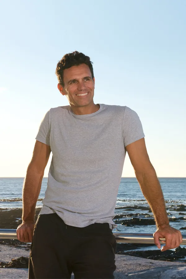 PRP-and-Stem-Cell-Microneedling-for-Stomach-Treatment A man with a toned midsection stands by the ocean. Get PRP and Stem Cell Microneedling for Stomach Skin Tightening from Blessed Beauty Boutique in Greater Phoenix.