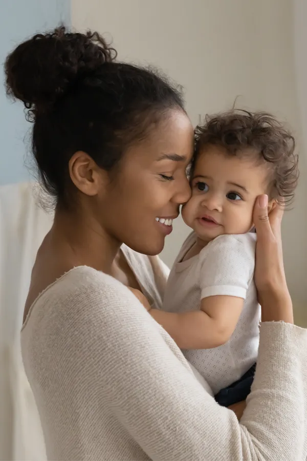 Postpartum-Hormone-Imbalance-Treatment A black woman happily touches her forehead to her infant's head. Get treatment for postpartum hormone imbalance from Blessed Beauty Boutique in Greater Phoenix.
