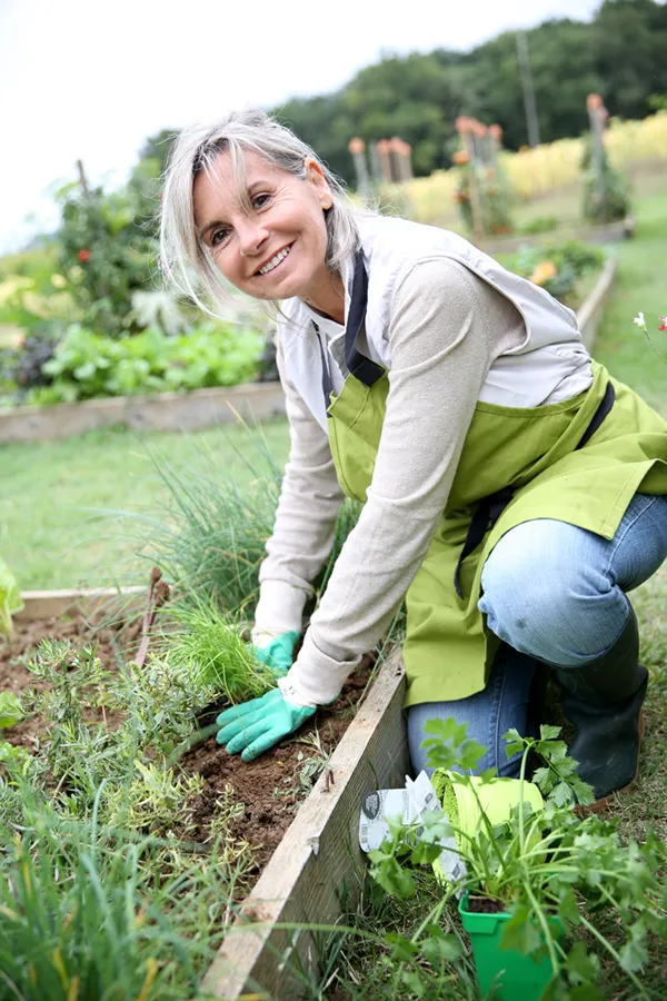 Rheumatoid-Arthritis-Treatment A mature woman bending down working on her garden happily after successful rheumatoid arthritis treatment from Blessed Beauty Boutique in Greater Phoenix.