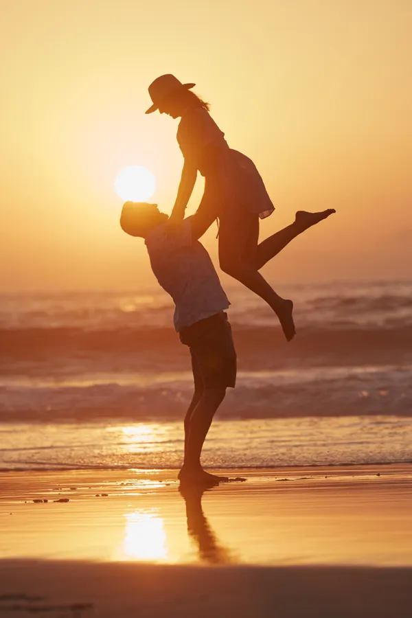 T-Shape-2-Body-Contouring-Treatment A man lifts a woman in the air at sunset on the beach. Get T-Shape 2 Body Contouring Treatment from Blessed Beauty Boutique in Greater Phoenix.