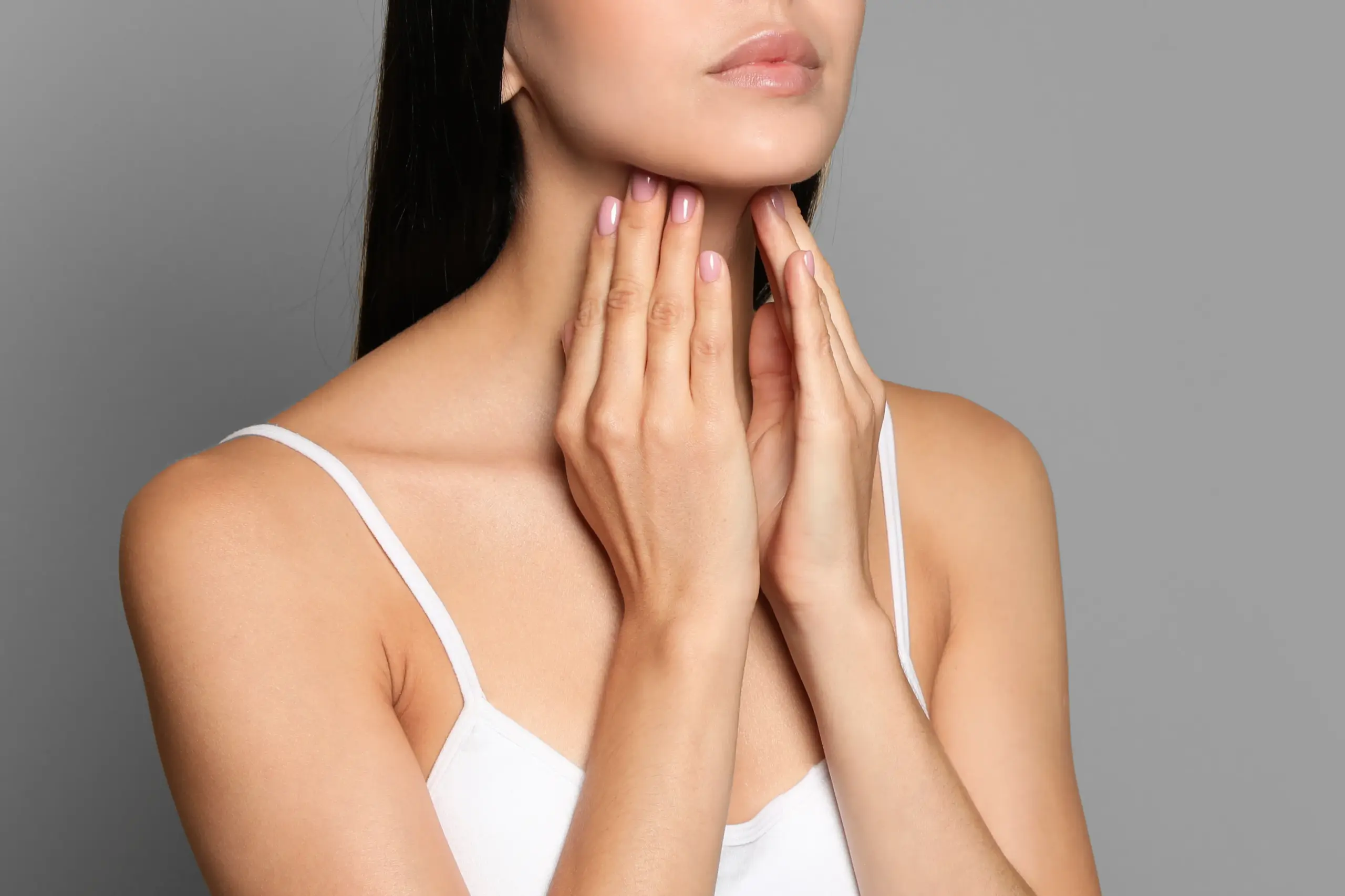 Thyroid-Doctor A woman in a white tank top touches her neck looking for signs of thyroid disorder. Get help for thyroid disorders from Blessed Beauty Boutique in Greater Phoenix.
