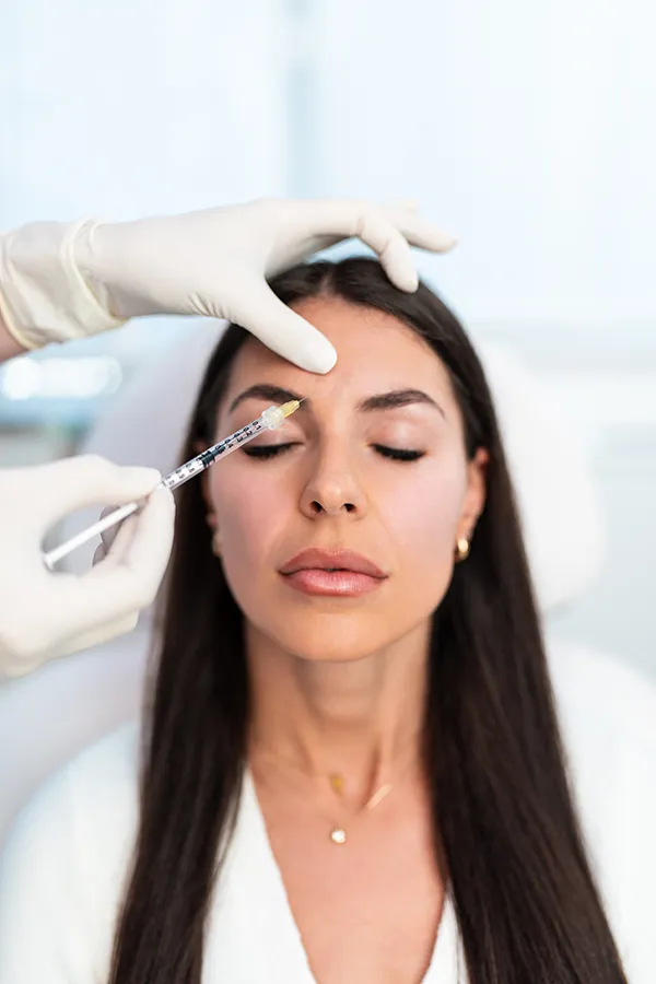 Versa-Fillers-Treatment A woman with long dark hair getting facial filler injections from a clinician. Get Versa filler treatments from Blessed Beauty Boutique in Greater Phoenix.